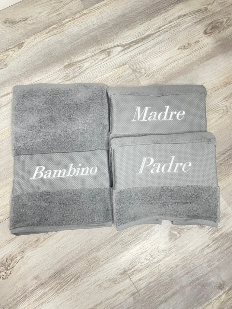 Gray towels labeled 'Madre', 'Bambino', and 'Padre' on a wooden surface