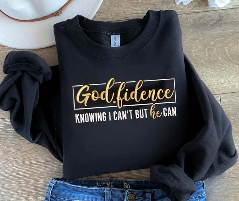 Black sweatshirt with gold and white text on a wooden surface