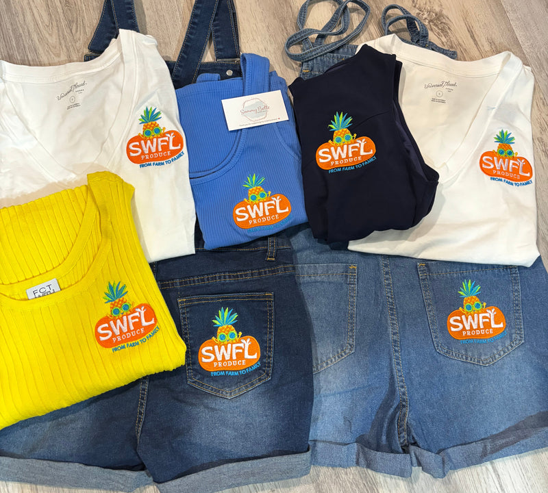 Collection of jeans and shirts with embroidered 'SWFL produce' branding on them on a wooden surface