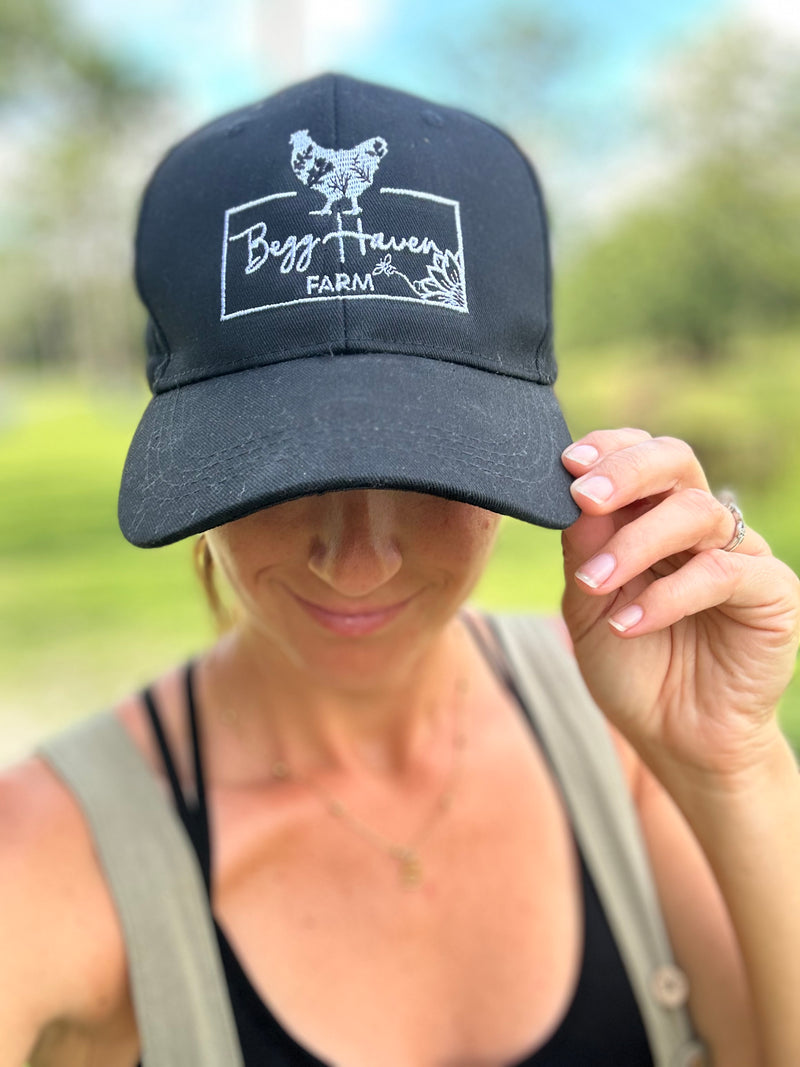Person wearing a black cap with a logo and text, outdoors.